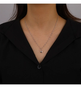 Close-up of a silver Figaro chain necklace featuring a delicate heart lock pendant