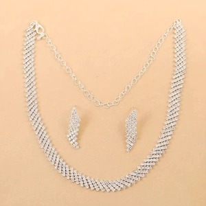 Dettaglio del set di gioielli da sposa con strass a forma di fulmine su sfondo beige chiaro