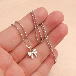 Detail of silver beaded ball chain necklace with polished bow tie pendant on hand