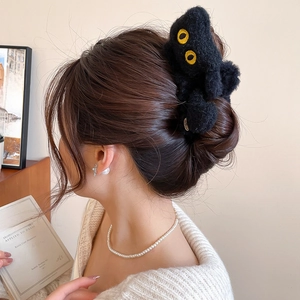 Détail de la pince à cheveux chat en peluche noire sur modèle pour un style de coiffure cosy