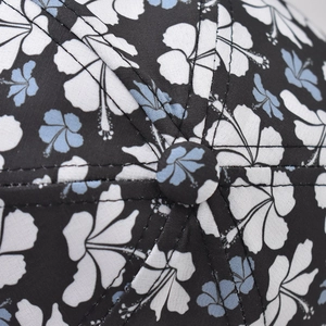 Close-up of cotton baseball cap crown featuring blue floral print and fabric button
