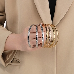 Detailed view of stacked heart-engraved bangles in silver, gold, and rose gold finish