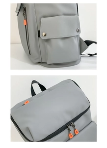 Detail view of water-resistant gray travel backpack with orange zipper accents