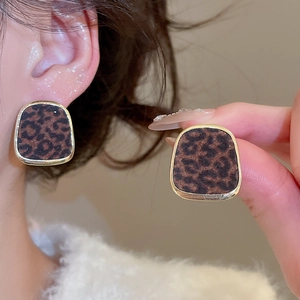 Détails de boucles d'oreilles carrées léopard avec cadres dorés sur un modèle