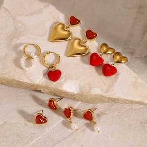 Detailsammlung von goldenen Herzohrringen und Perlensteckern auf strukturierter Steinplatte