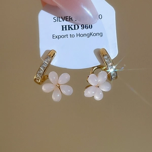 Detail of 18k gold plated flower stud earrings featuring clear cubic zirconia and resin petals