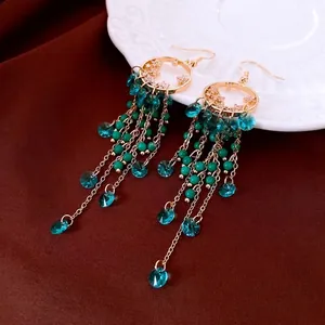 Bohemian gold circle earrings with crystal tassels and turquoise beads on dark velvet