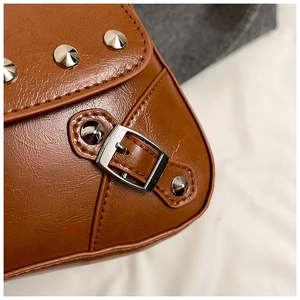 Close-up of brown litchi grain leather bag with silver conical rivets and metal buckle