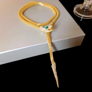 Detailed macro view of the gold serpent necklace with green gemstone eyes and pavé crystals