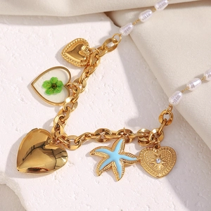 Nahaufnahme goldener Amulett-Anhänger mit weißen Perlen und blauem Seestern an einer Kette