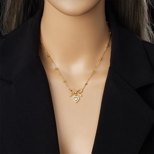 Élégant collier nœud doré avec pendentif cœur et chaîne à perles porté par un mannequin