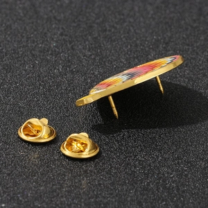 Macro shot of colorful enamel Ferris wheel brooch with golden butterfly clasps on black