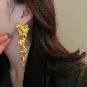 Elegant gold hollow flower tassel drop earrings on model with sophisticated drape effect