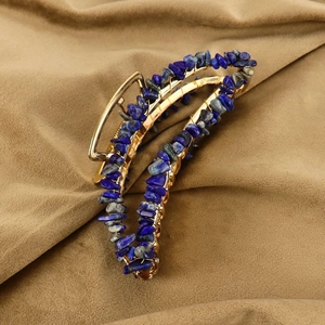 Detail of handmade gold hair claw clip featuring natural blue crystal stone wire wrap