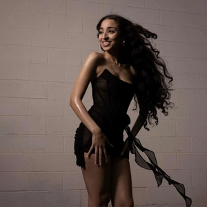 Detail view of black strapless mini dress with mesh fabric ruffles and side streamers
