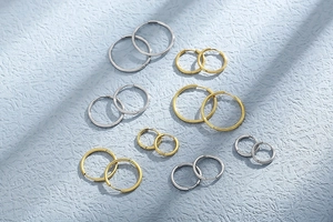 Flat lay of multiple sizes of gold and silver stainless steel hoop earrings set