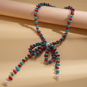 Detail of bohemian necklace with irregular red stones, turquoise beads, and pearl bow