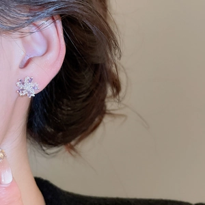 Close-up of elegant purple zircon flower stud earring worn by a model in warm light