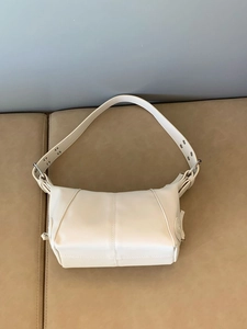 Close-up of white PU leather underarm bag featuring decorative seams and metal rivets