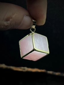 Pink quartz cube pendant necklace with gold plated edges shown in a close-up view