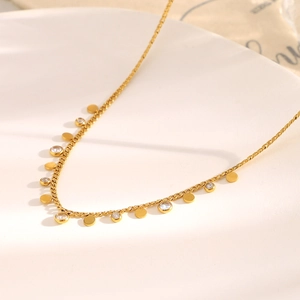 Detailed view of 18K gold plated disc and zircon pendants on a flat curb link necklace