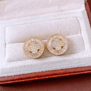 Close-up of gold round stud earrings with star zircon inlay in a beige velvet jewelry box