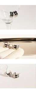 Macro detail of silver layered C-shaped hoop earrings with polished metallic mirror finish