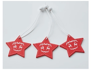 Close-up of red wooden star ornaments with white reindeer silhouette and stitching details