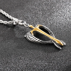 Macro detail of winged arrow pendant with gold and silver finish on rope chain