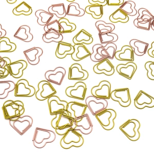 Flat lay of heart-shaped metal paperclips in gold and rose gold colors on white background