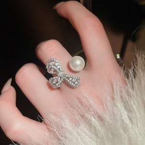 Close-up of adjustable silver bow ring with white pearl and sparkling cubic zirconia stones