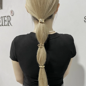 Detailed view of three gold wave-textured metal hair rings on a ponytail hairstyle
