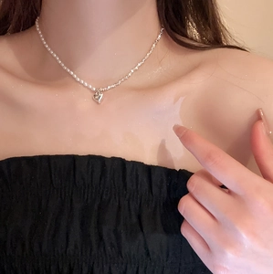 Collier à pendentif cœur argenté avec chaîne en perles sur la clavicule féminine
