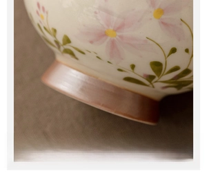 Macro shot of hand-trimmed ceramic cup base with daisy design on brown linen fabric