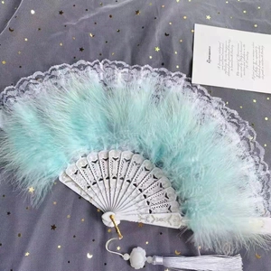 Détails d'éventail en plumes vert menthe avec manche blanc sculpté et pompon élégant