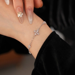Macro shot of silver zircon clover bracelet on wrist with elegant black velvet background