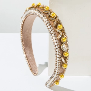 Détail d'un serre-tête en daim marron orné de strass brillants et de perles blanches chic