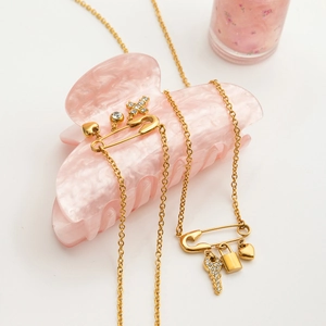 Gold paperclip necklace with heart and key charms on pink marble hair claw clip