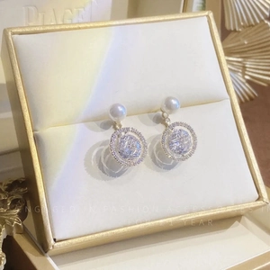 Détail de boucles d'oreilles perles dorées avec anneaux en zircon dans un coffret cadeau