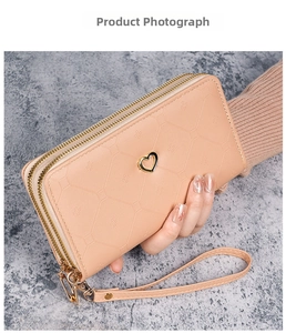 Macro view of long double zipper wallet with pink geometric patterns and heart clasp