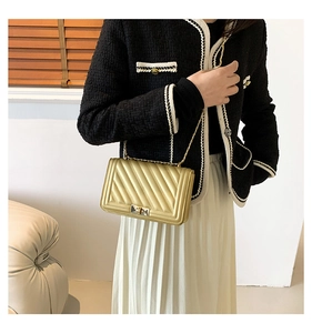 Detail of champagne gold quilted crossbody bag with metal chain strap and turn-lock
