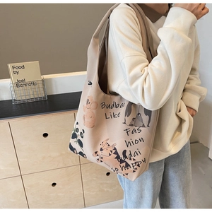 Detail view of khaki canvas tote bag featuring cute cartoon animal illustrations and artistic text