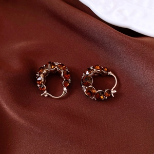 Macro shot of rose gold vintage earrings with amber crystals on brown silk fabric