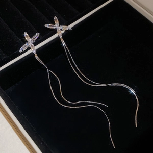 Détail de boucles d'oreilles pendantes argentées avec zircon en X et fines chaînes