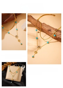 Detail of double-layer gold chain necklace featuring blue turquoise beads and tree of life charm