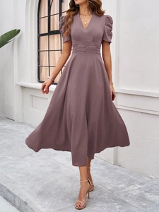 Detail of dark purple V-neck dress featuring puff sleeves and elegant pleated waistline