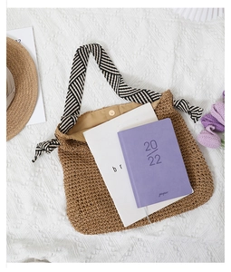 Flat lay of brown straw tote bag with striped fabric handles and summer accessories