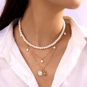 Close-up of layered necklace with pearls, starfish, and shell pendants on model