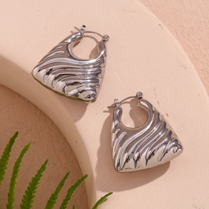 Close-up of silver hollow trapezoid earrings with wavy texture on minimalist display