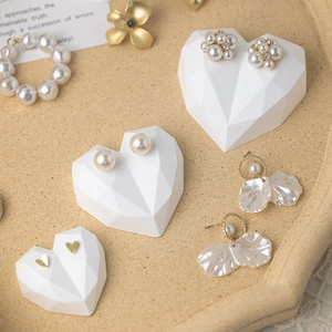 Elegant heart-shaped jewelry display stand featuring pearl and gold heart stud earrings